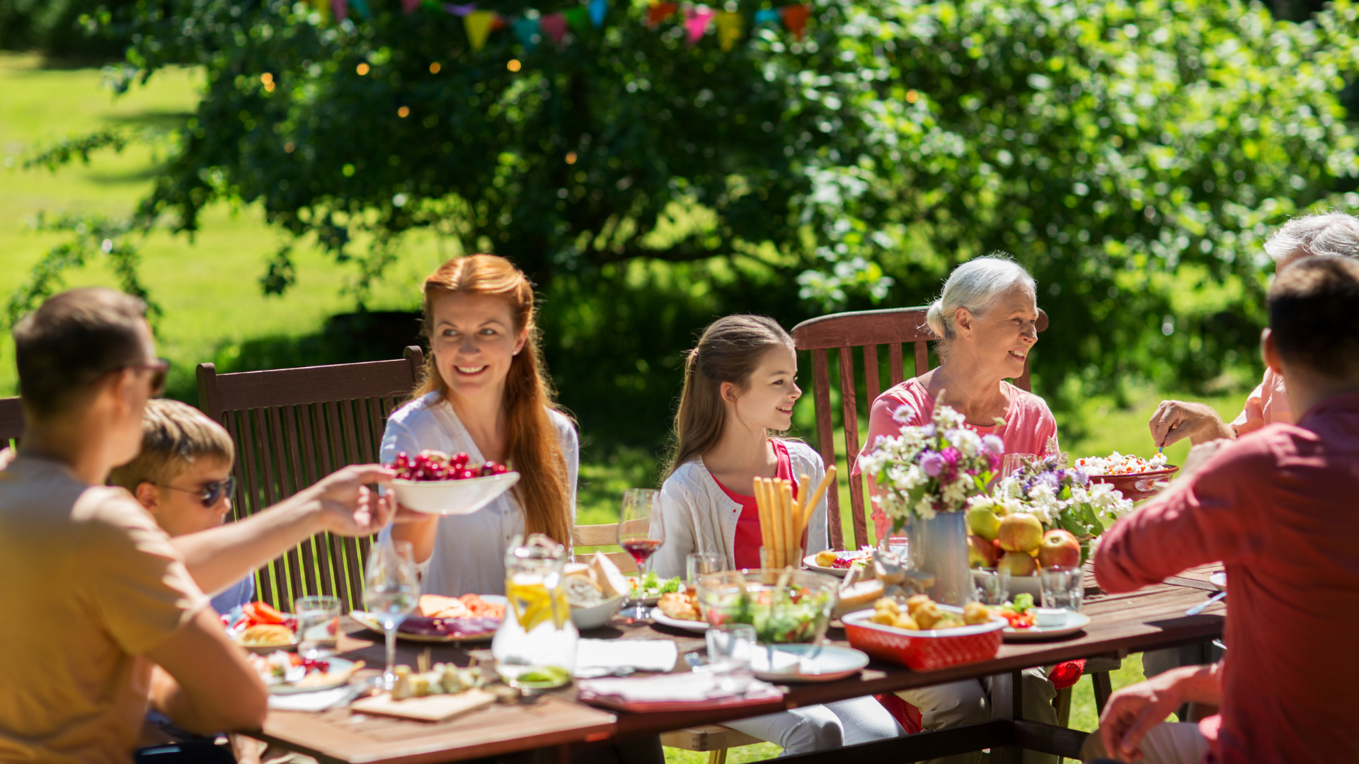 A large family enjoying an outdoor lunch in their backyard.