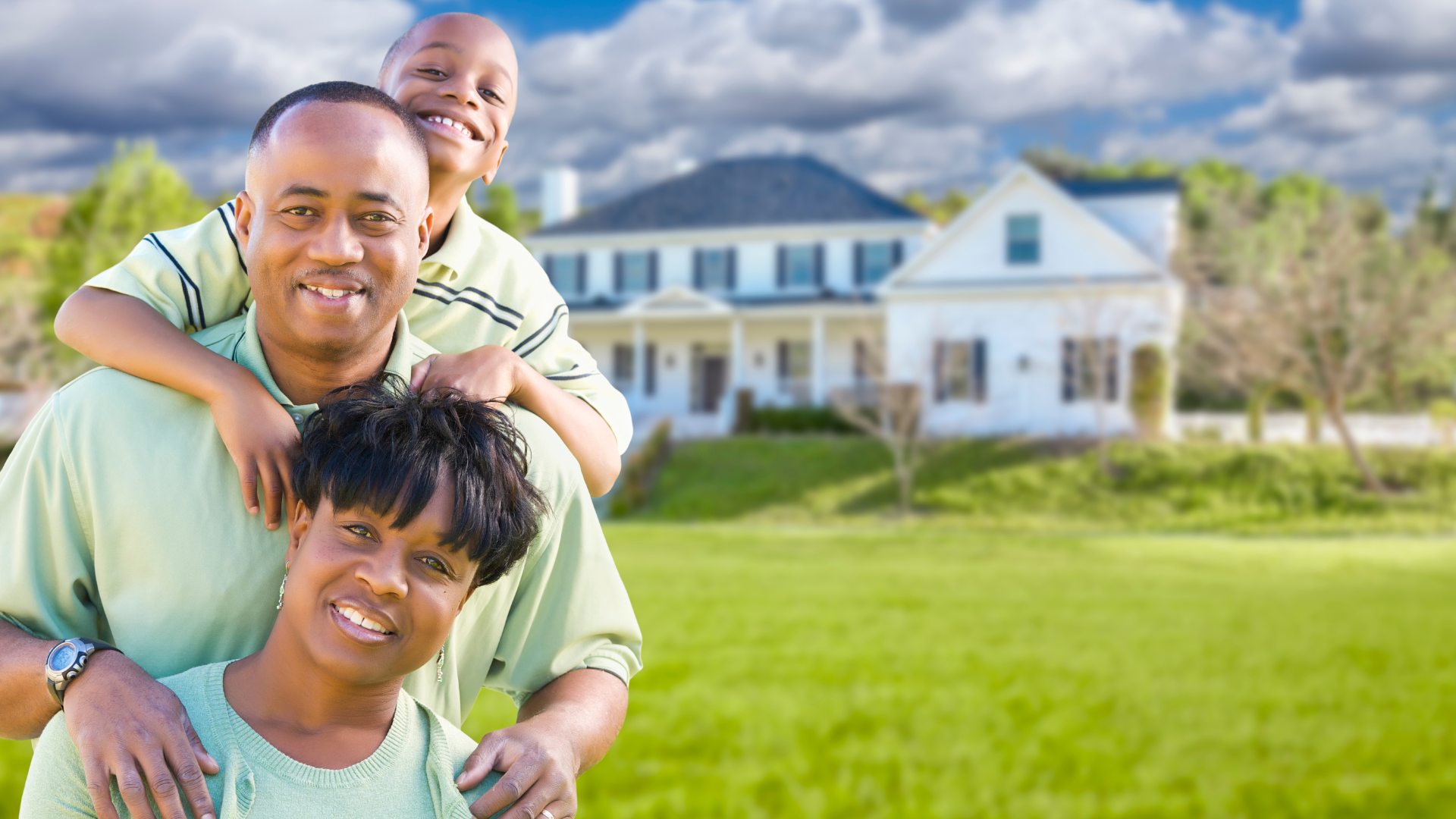 Two parents and their young son standing in the front yard of their home.