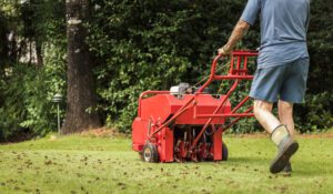 man using aerating equipment to aerate home lawn scaled