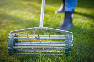 person using aerator on green lawn