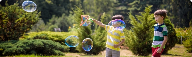 Two kids playing with bubbles in their backyard.