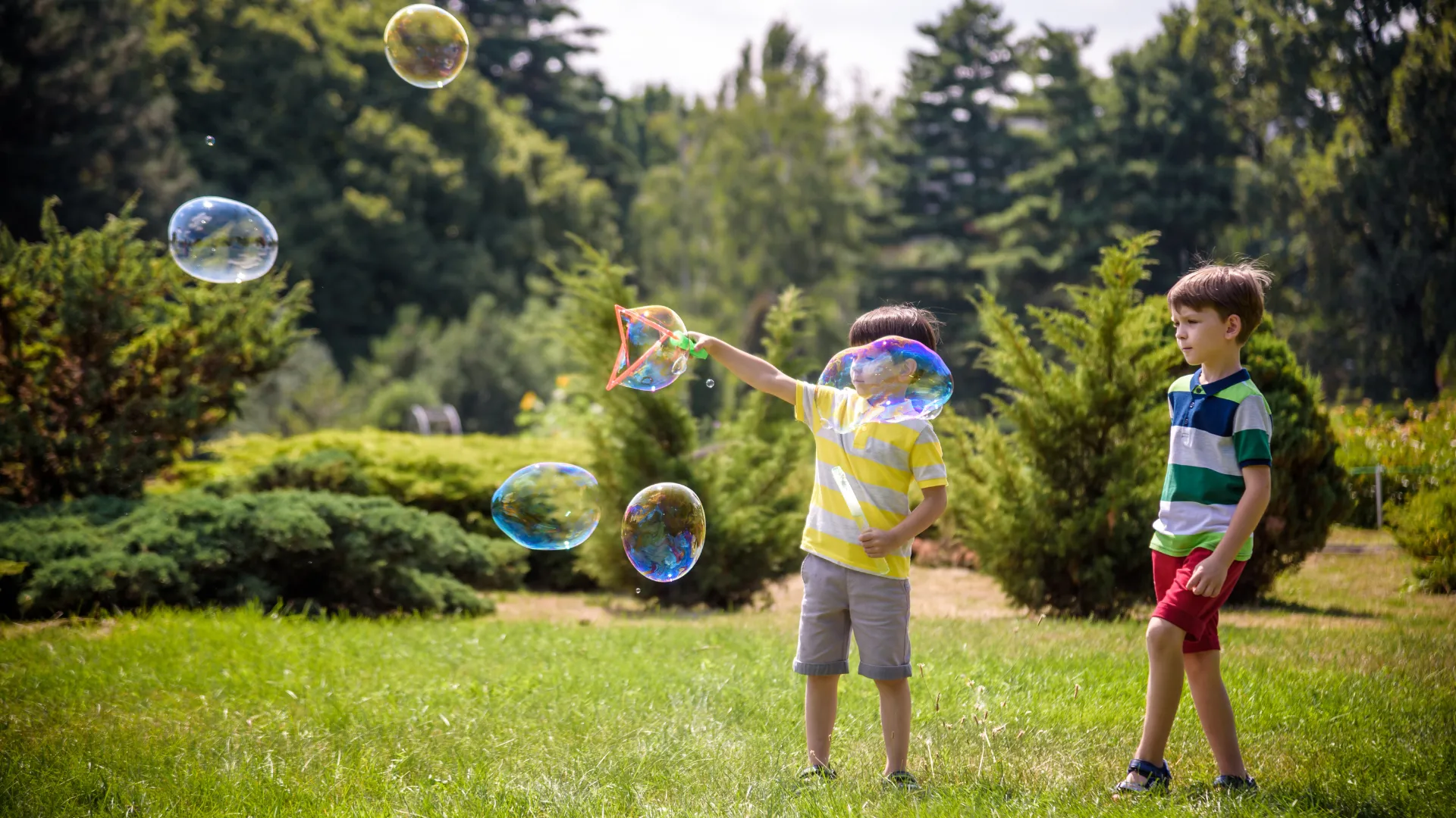 Two kids playing with bubbles in their backyard.